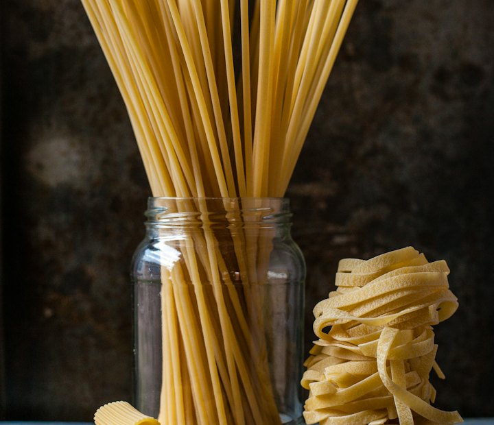 Verschiedene Sorten getrockneter Pasta: Spaghetti im Glas, Rigatoni und Tagliatelle
